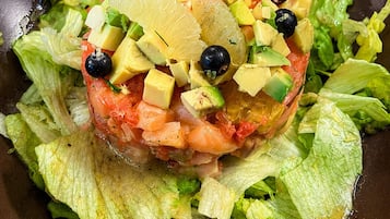 Une salade composée d’avocat, de tomates et d’olives noires, servie sur un lit de laitue.