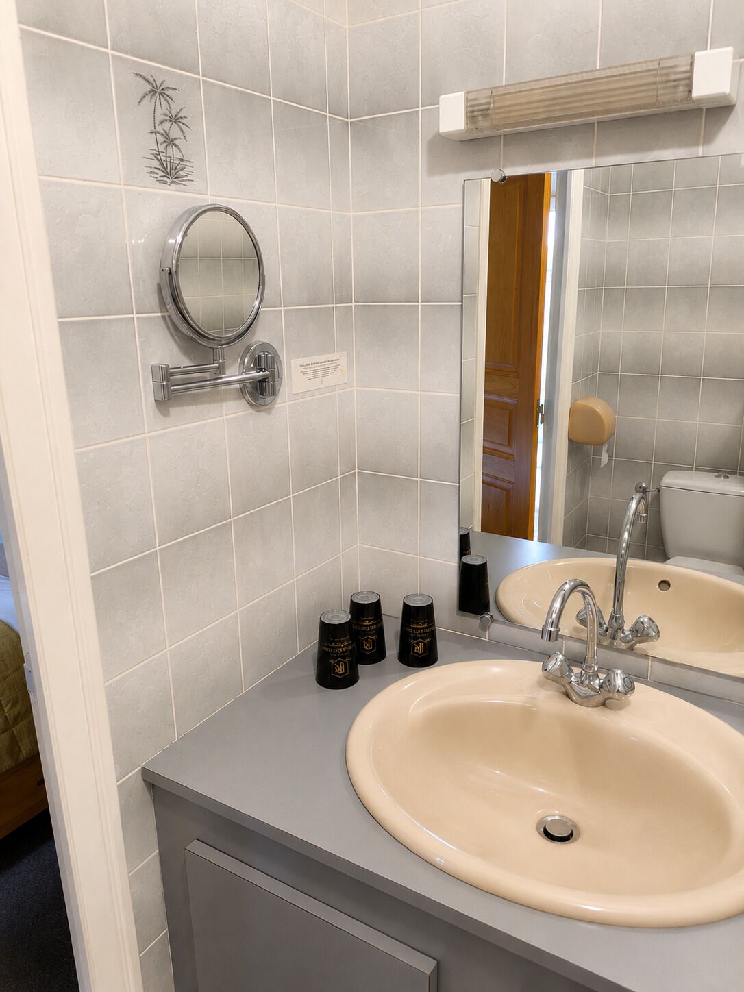 A bathroom with a round mirror, a sink, and a toilet.