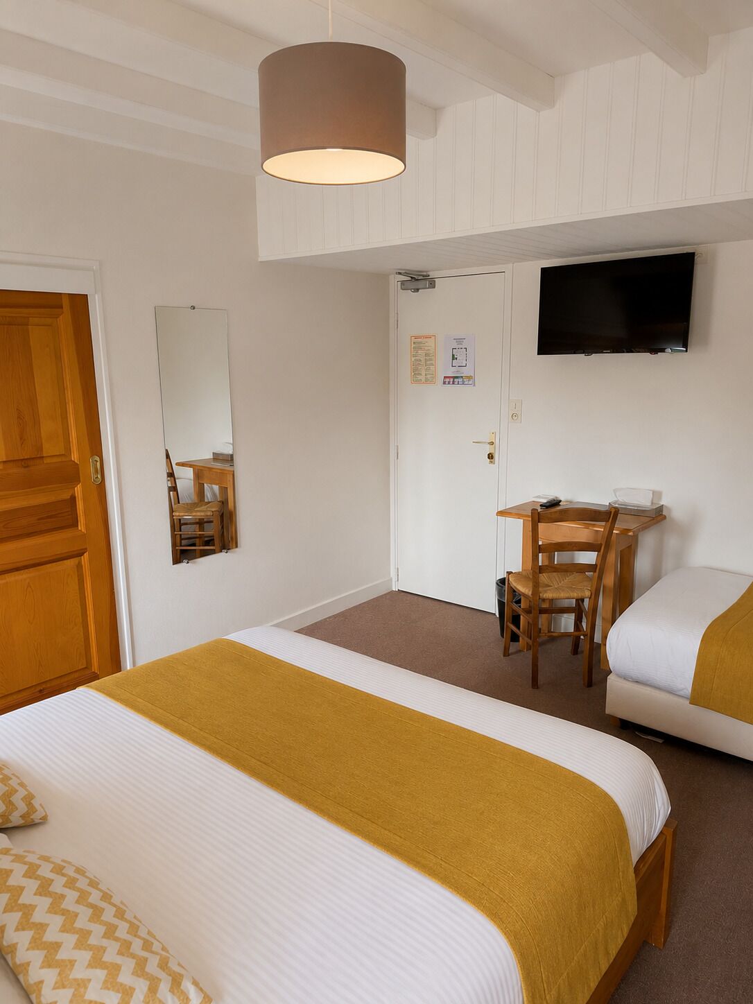 Una habitación de hotel con cama, escritorio, silla, televisor y puerta.