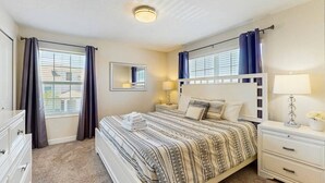 Ein Schlafzimmer mit einem Bett, Nachttischen, einem Spiegel und Vorhängen.