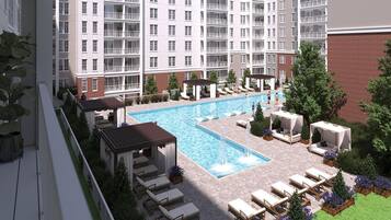 A rooftop pool with lounge chairs, a gazebo, and a view of a multi-story building.