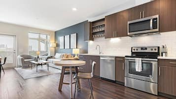 A modern kitchen with dark wood cabinets, stainless steel appliances, and a dining area with a round table and chairs.