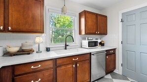 A kitchen with wooden cabinets, a white countertop, a sink, a microwave, and a dishwasher.