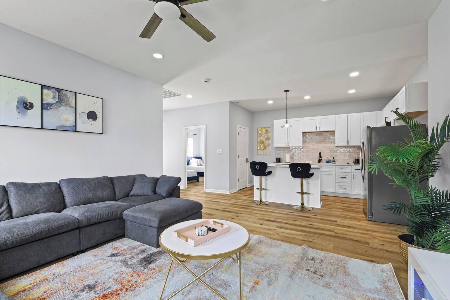 A modern living room with a grey sofa, a small round table, and a colorful rug.