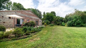 Een gebouw van steen met een bakstenen gevel, een gazon en omliggende beplanting.