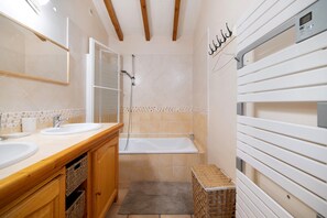 Un bagno con due lavabi, una vasca, armadietti in legno, un cesto di vimini e un porta asciugamani.