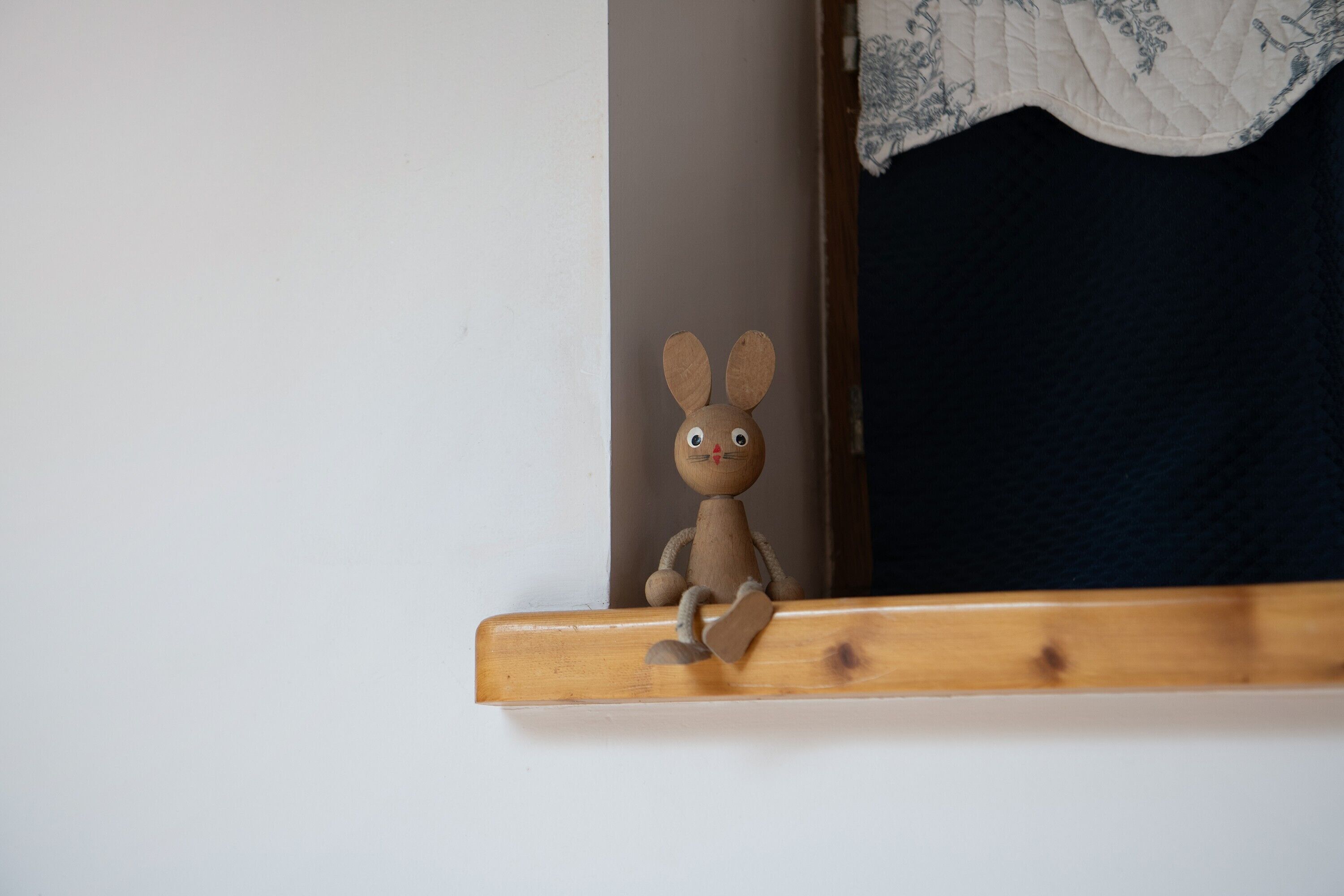 A wooden toy rabbit on a shelf.