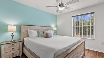 A bedroom with a bed, nightstands, a ceiling fan, and a window with a view.