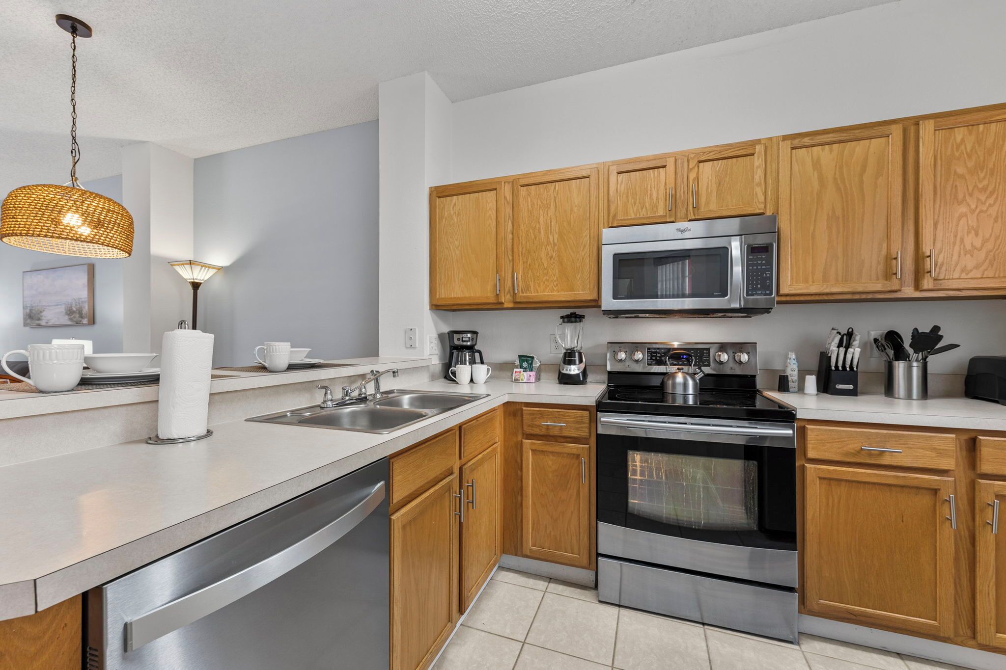 A modern kitchen with stainless steel appliances, wooden cabinets, and a white countertop.