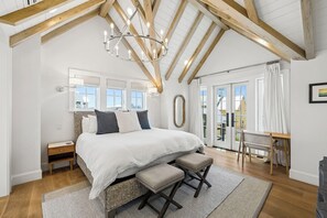Ein Schlafzimmer mit einem großen Bett, Holzbalken, einer Chandelüster, einem kleinen Tisch und einer Bank.