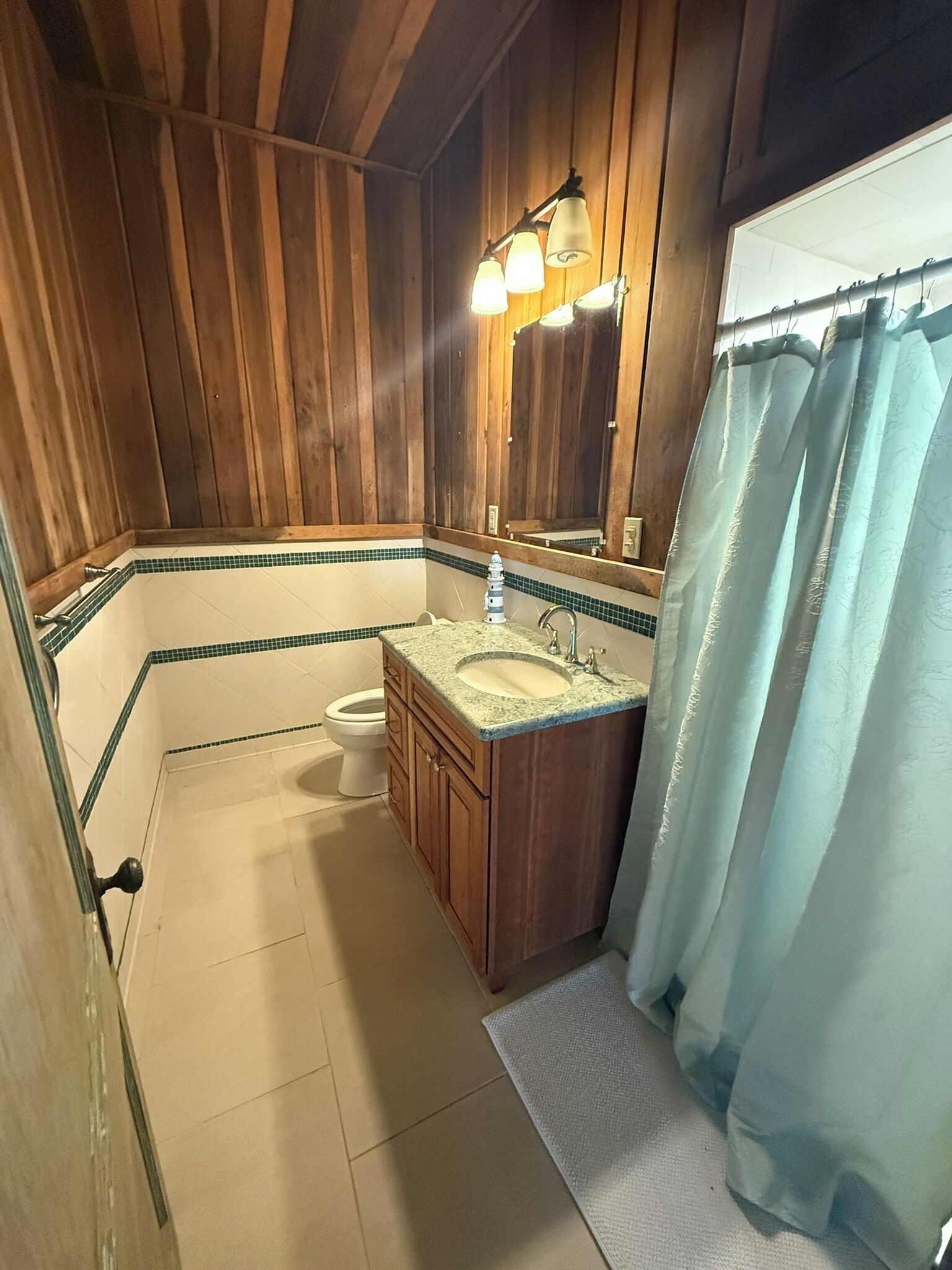 Un baño con paredes de madera, un lavabo, un inodoro y una cortina de ducha.