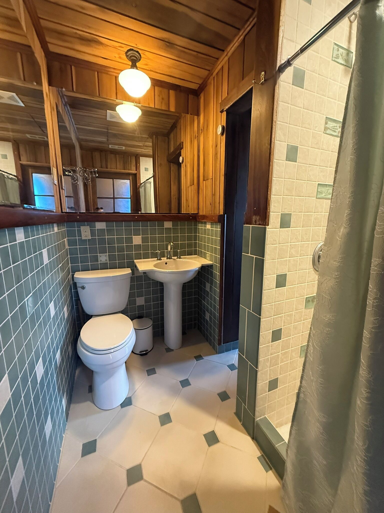 A compact bathroom with a toilet, sink, and shower area.