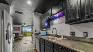 Una cocina moderna con armarios oscuros, un lavamanos de acero inoxidable y un letrero de neón.