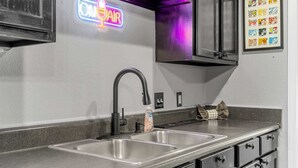 Una cocina con un lavamanos doble, un letrero de neón y una colección enmarcadas de logotipos de MTV.