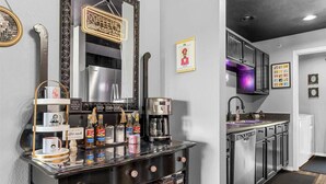 Una zona de bar con una máquina de café, estantes con condimentos, un espejo y un letrero de neón.