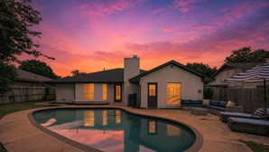 Un pati amb piscina, una casa i mobiliari exterior.