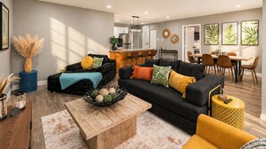 A modern living room with a black sofa, yellow armchair, and a coffee table. - Near AT&T Stadium | 3/2 Home with Boho Vibes (Arlington)