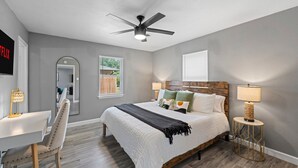 A bedroom with a bed, a desk, a chair, a ceiling fan, and a window. - Near AT&T Stadium | 3/2 Home with Boho Vibes (Arlington)