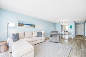 A living room with a sofa, armchair, and dining table. - The 312 at 69th Ave: Poolview Retreat (Myrtle Beach)