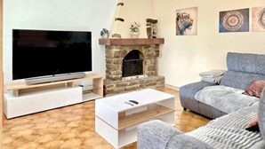 Ett vardagsrum med tv, öppen spis, soffa och soffbord.