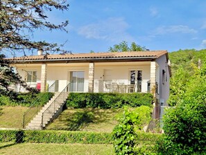 Ein zweistöckiges Haus mit Balkon, Treppe und Garten.