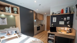 Een moderne slaapkamer met een bed, nachtkastje en een bureau met een laptop.
