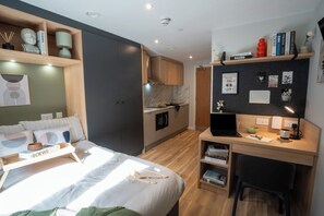 Ein modernes Schlafzimmer mit Bett, Nachttisch und Schreibtisch mit Laptop.
