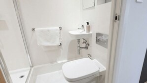 Een moderne badkamer met een douchecabine van glas, een witte wastafel en een toilet.