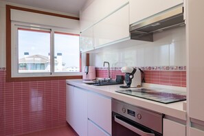 Una cocina moderna con ventana, salpicadero de azulejos rosas y electrodomésticos de acero inoxidable.