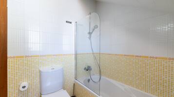 Un baño con ducha, inodoro y pared de azulejos.