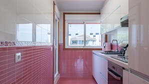 A modern kitchen with red tiles, a window, and a view of buildings outside. - Penthouse in Palmeira with Sea Views, Shared Pool, Tennis Court and Wi-Fi (Insuela)