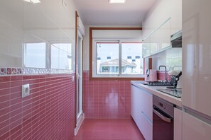 A modern kitchen with red tiles, a window, and a view of buildings outside.