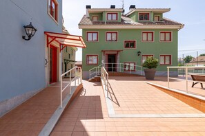 Un bâtiment dont l’entrée est encadrée de rouge, qui possède un balcon et une plante en pot.