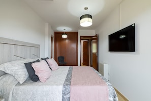 A bedroom with a bed, pillows, a TV, and a chair. - Penthouse in Palmeira with Sea Views, Shared Pool, Tennis Court and Wi-Fi (Insuela)