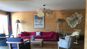 Un interior de madera con un sofá rojo, un sillón azul y una silla blanca.