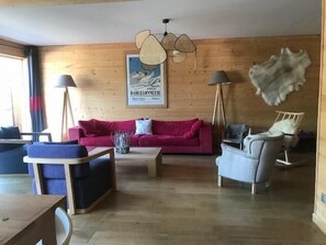 Ein Holzinterieur mit einem roten Sofa, einem blauen Sessel und einem weißen Stuhl.