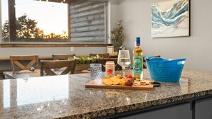 Eine Küchenarbeitsplatte mit Schneidebrett, Snacks, einer Flasche und einem Glas.