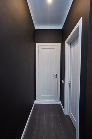 Un couloir aux murs sombres, une porte blanche et un chambranle de porte blanc.