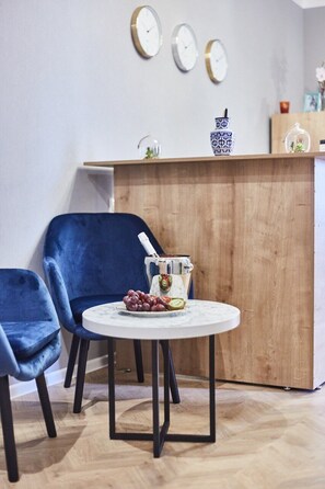 Une piĂšce comprenant une table ronde, deux chaises bleues, un comptoir en bois et trois horloges murales.
