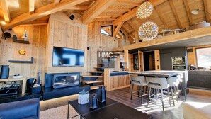 Un interior moderno con televisor, paredes de madera, una zona de bar y una escalera.