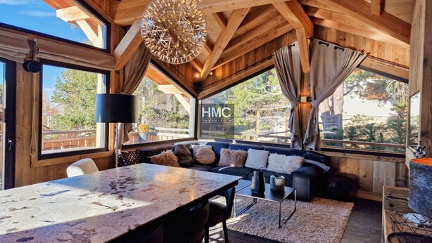 Una habitación acogedora con una mesa grande, un sofá con cojines y una lámpara colgante.