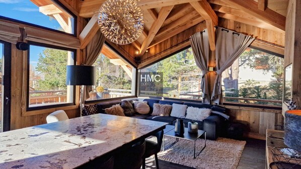 A cozy room with a large table, a sofa with cushions, and a hanging light fixture. - Chalet "L'Oustal", superbe vue et Jacuzzi (Bolquère)