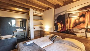 A hotel room with a bed, a bathroom with a sink, and a large poster on the wall.