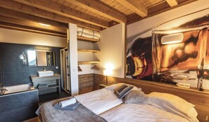 A hotel room with a bed, a bathroom with a sink, and a large poster on the wall.