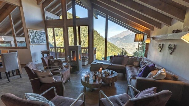 A cozy interior with a fireplace, wooden furniture, and a mountain view.