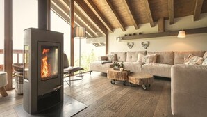 A cozy living room with a wood-burning stove, a sofa, and a dining table.