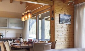 A wooden interior with a dining area, wooden walls, and a large window.