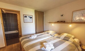 A room with two beds, a shower area, a framed picture, and a shelf with lights.
