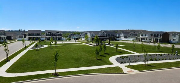 Zona residencial com casas modernas, gramados verdes e céu claro.