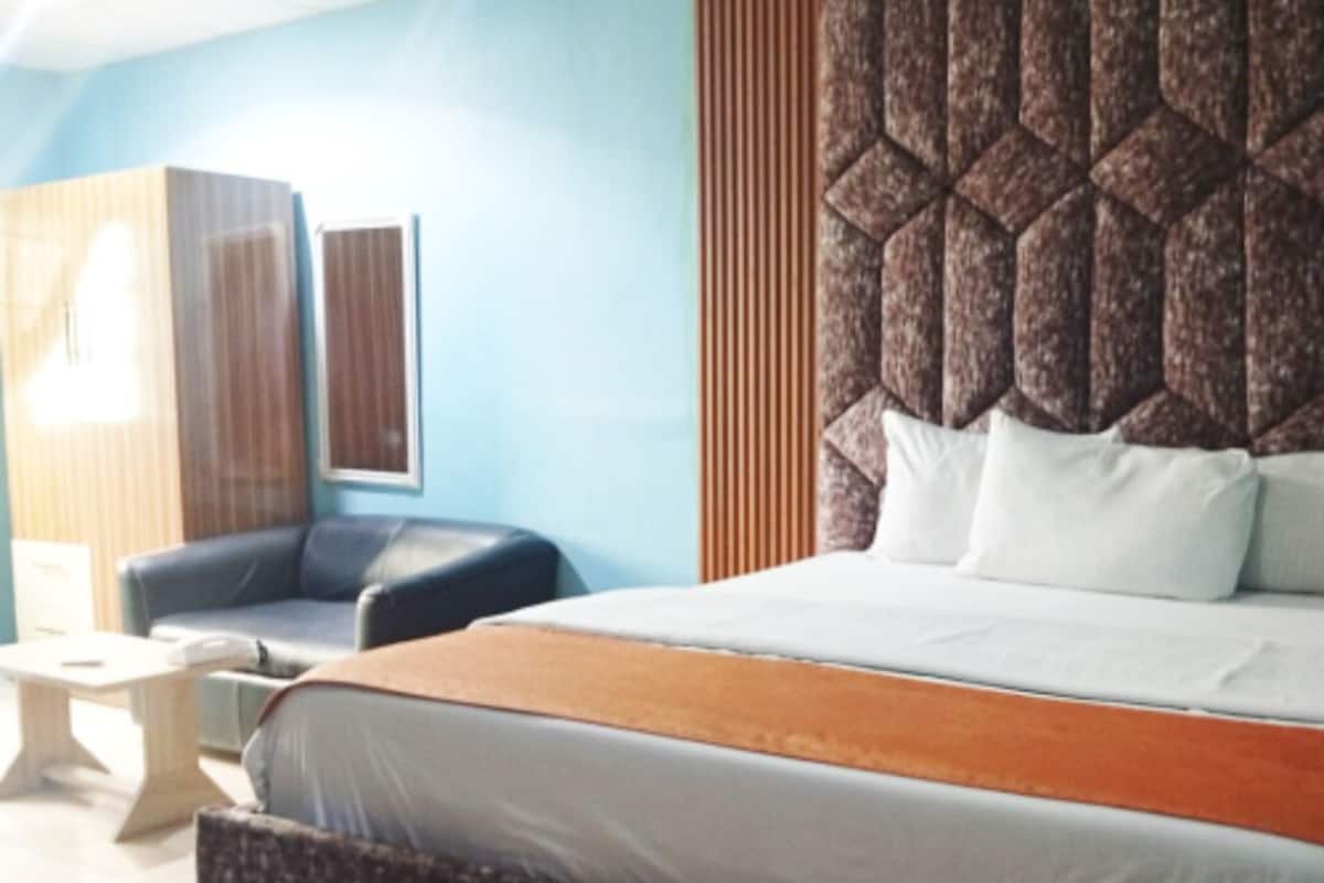 Ein Hotelzimmer mit einem Bett, einem Schlafsofa, einem kleinen Tisch und einer Wand mit strukturierter Gestaltung.